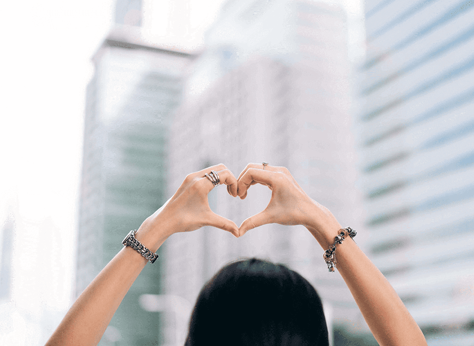 Hands in heart shape with blurred building in background