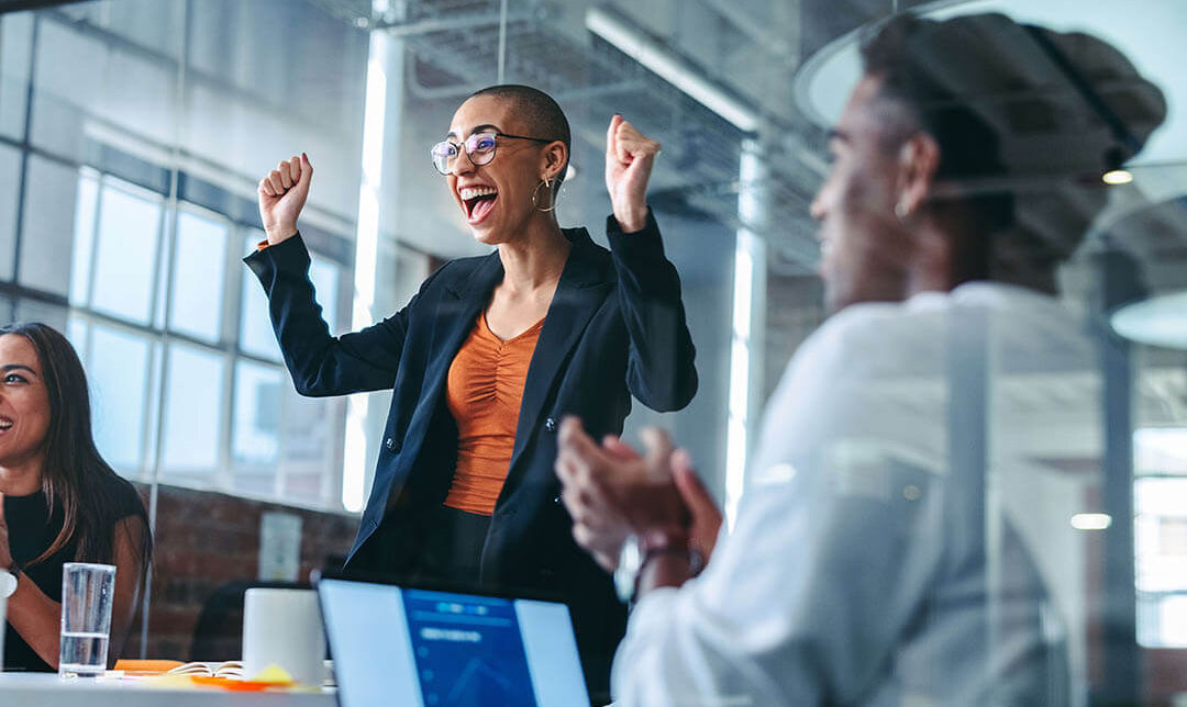 Young businesswoman being applauded by her colleagues in a modern office. Happy young businesswoman receiving praise from her team