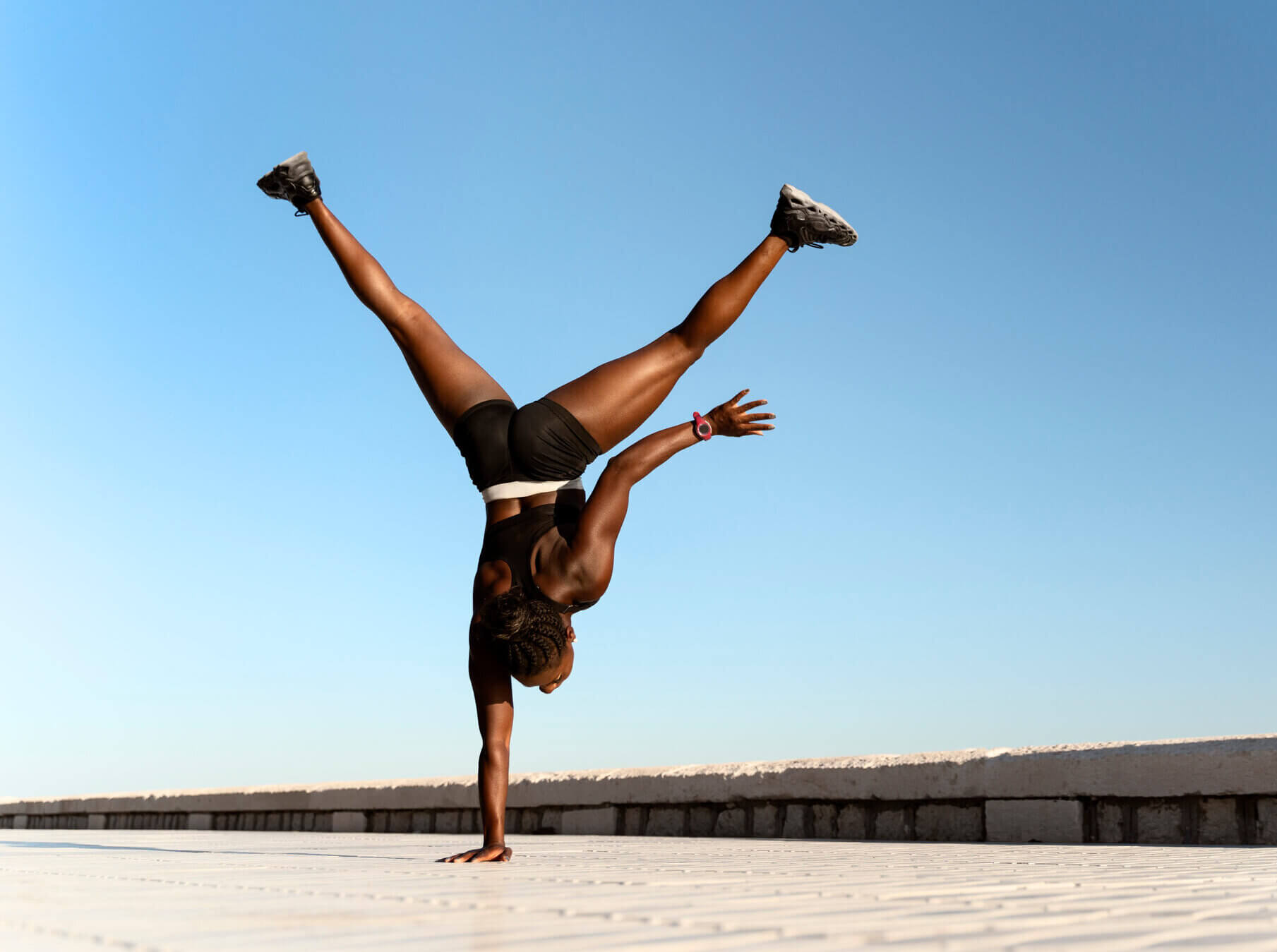 Back view of the woman doing yoga and standing on her hands near the sea in the morning. Sport and recreation concept