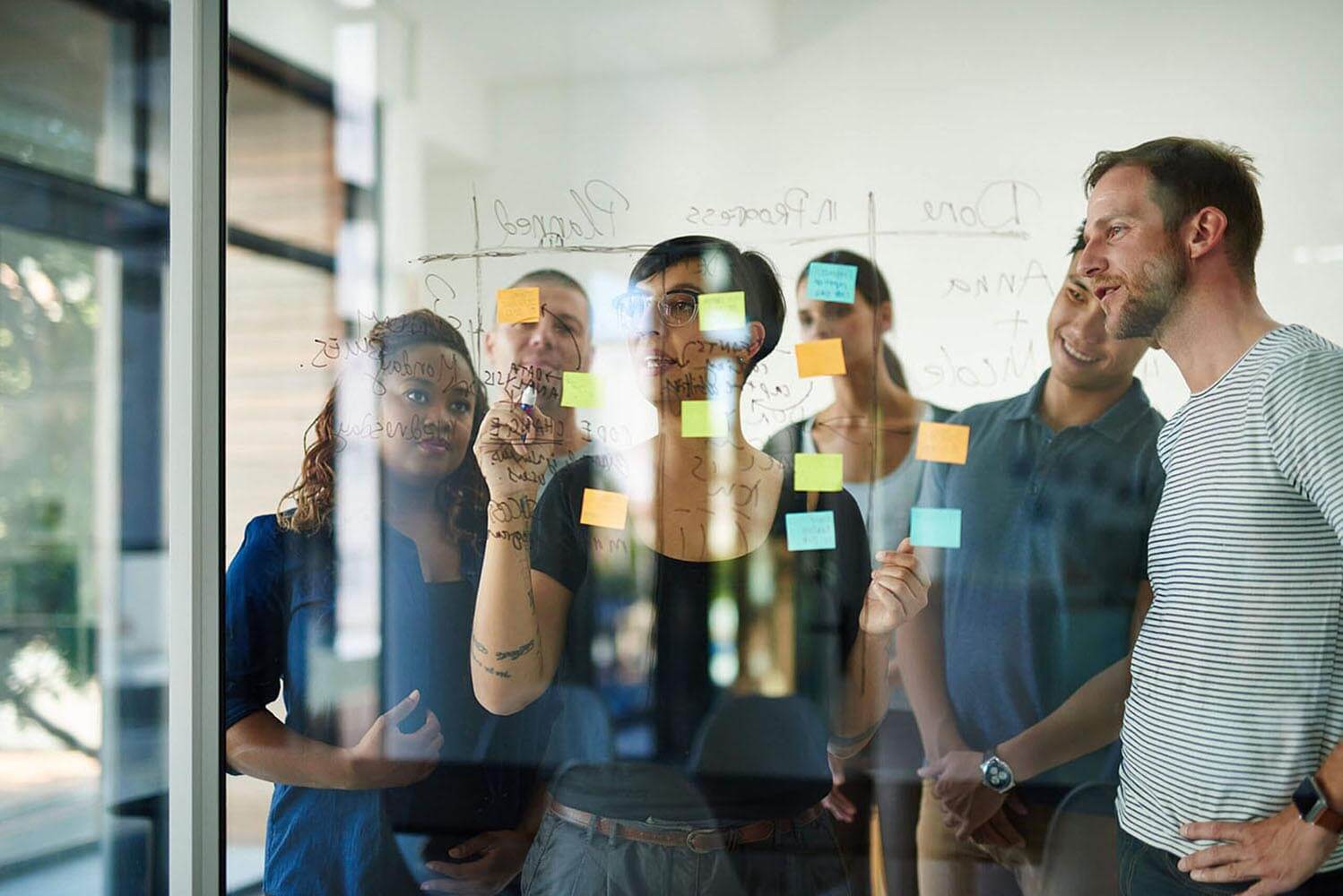 group of young designers planning on a glass board