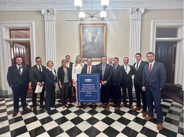 A group of individuals standing in a formal room with checkered flooring at the White House