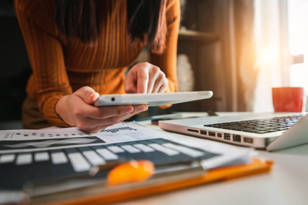 Automotive SEO expert in orange sweater reviews predictive metric insights on a tablet