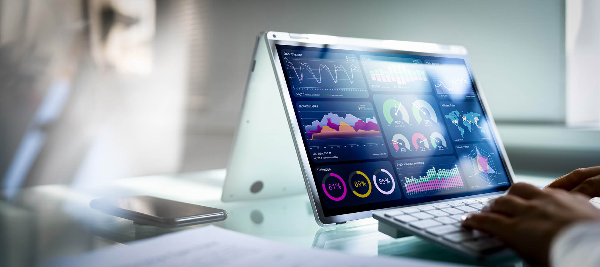 A laptop with a touchscreen displaying various colorful graphs and data analysis charts, including bar graphs, pie charts, and percentage indicators.