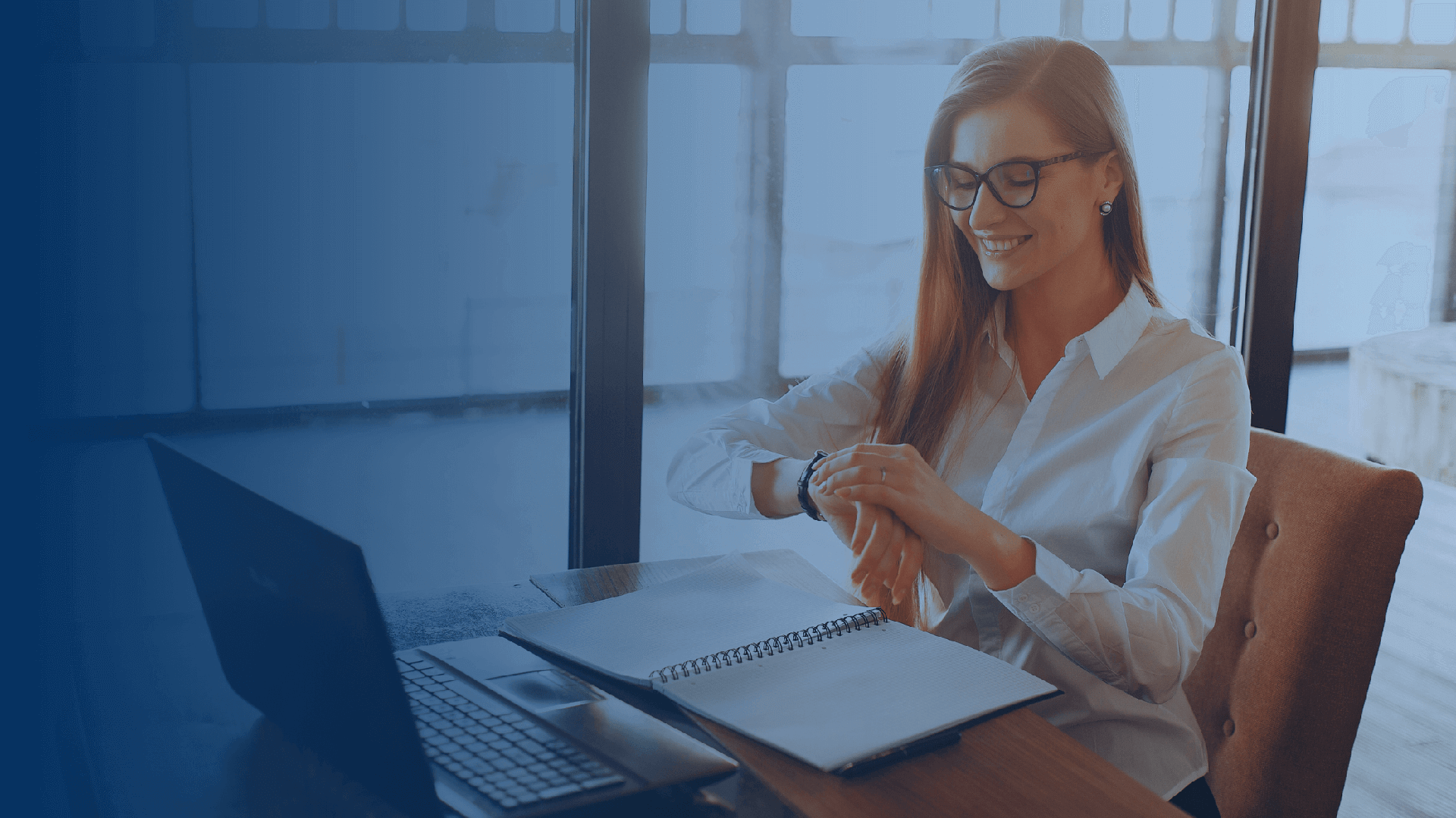 woman checking the time on her watch at her desk in f