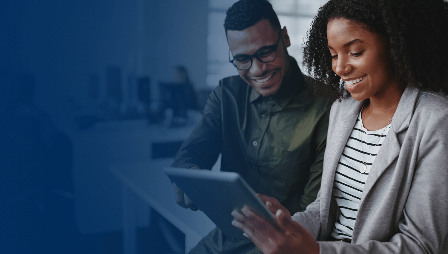 two people in business casual dress looking at a tablet