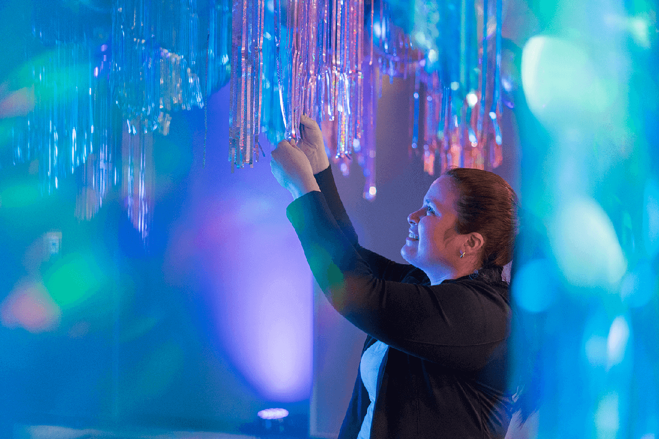 woman hanging lights on blue background