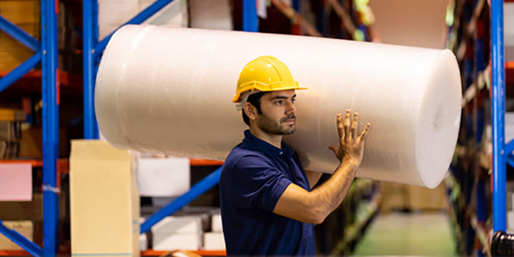 construction working carrying large roll of bubble wrap