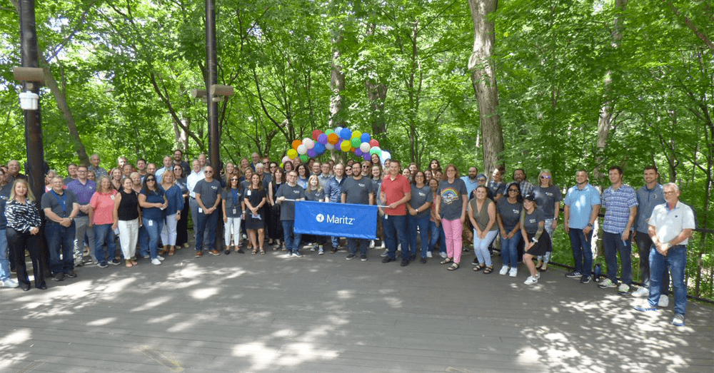 A group attending the pride event and holding a Maritz banner.