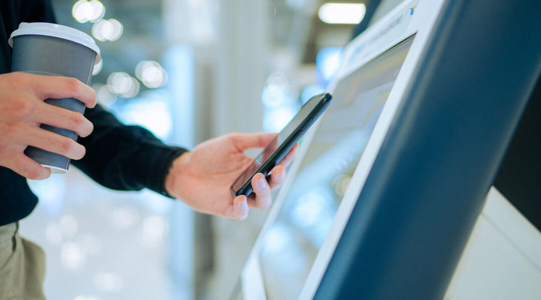 person holding their cell phone up to a computer monitor to check in to a conference