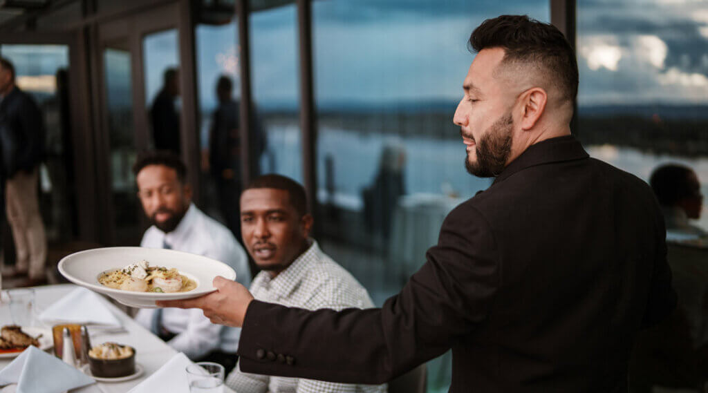 waiter serving food to a restaurant table of guests
