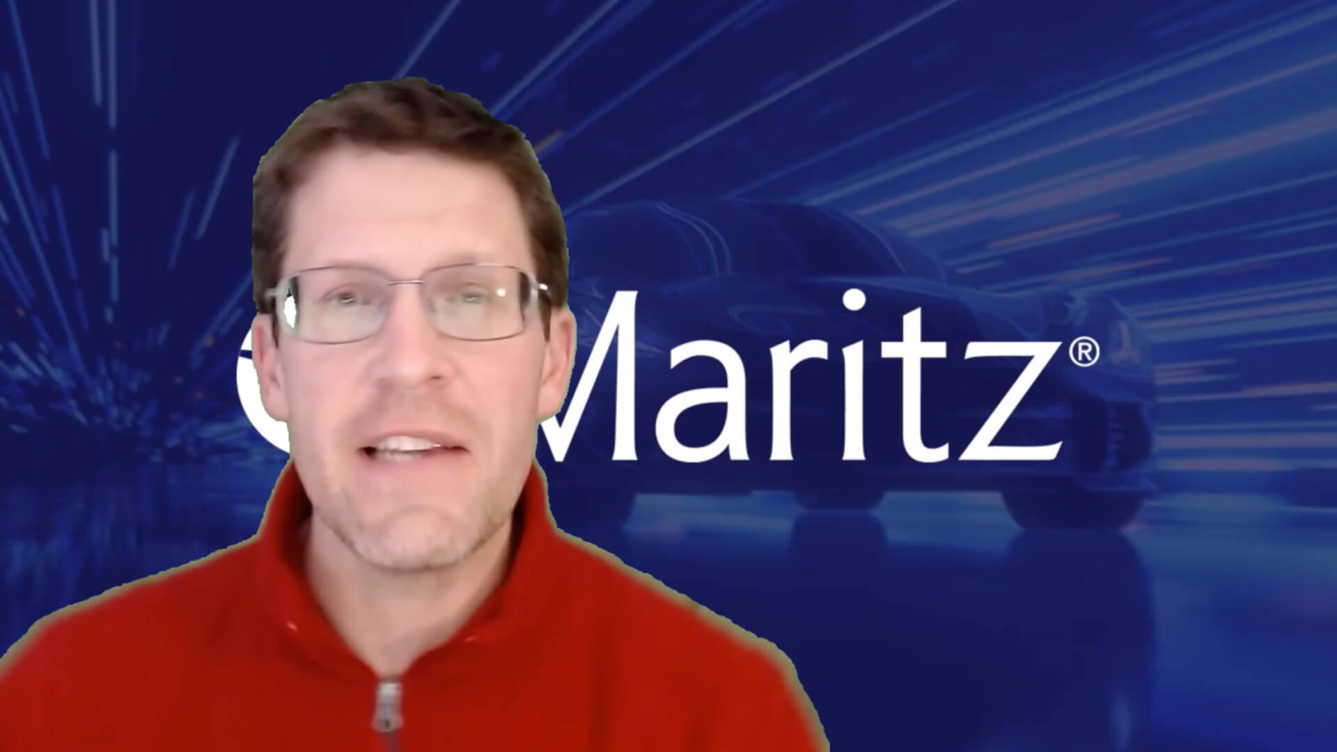 A person wearing a red zip-up sweater sits in front of a digital Maritz background featuring a stylized car silhouette and blue motion‑streak graphics.