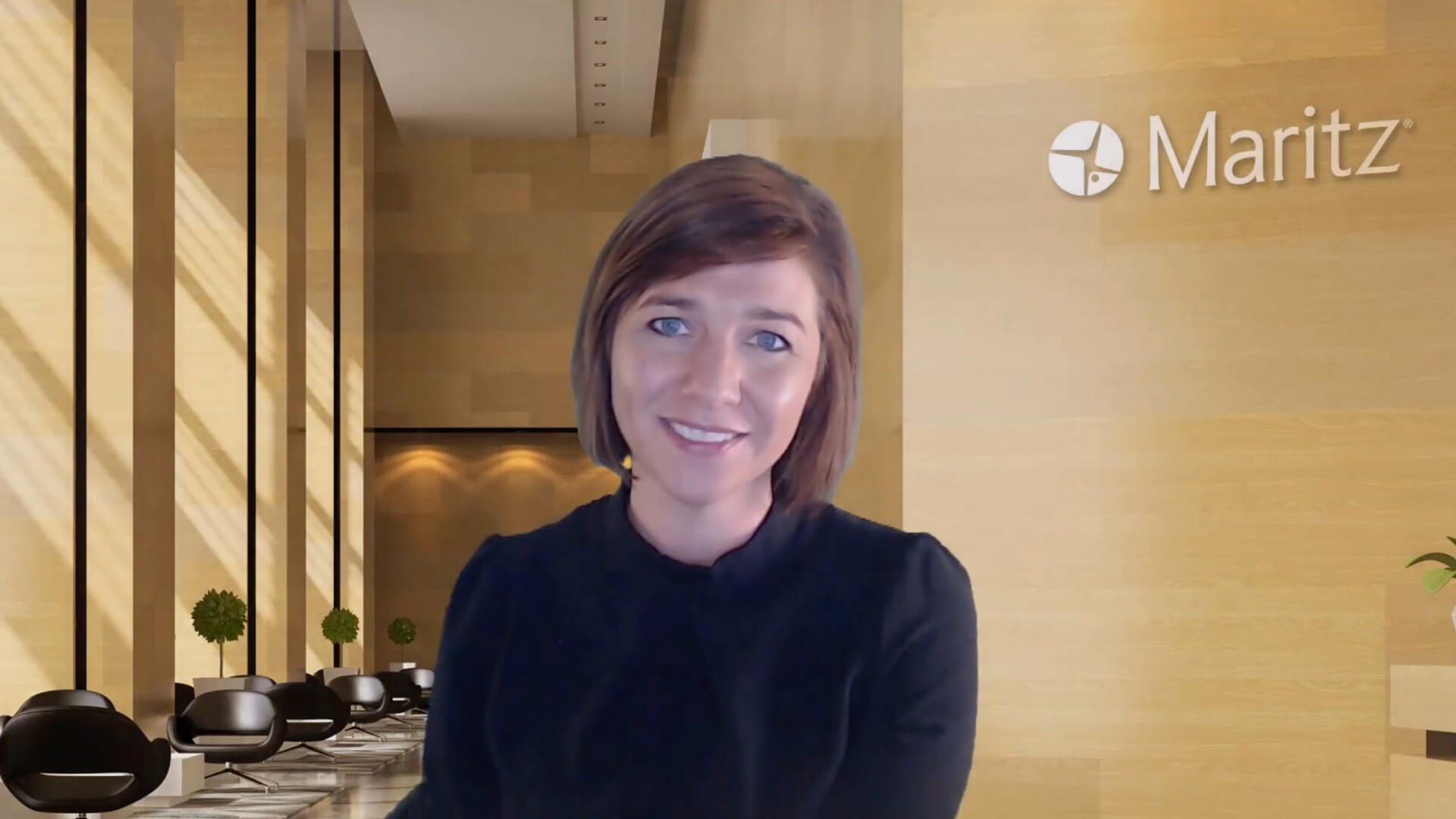 Person sitting in a modern, light‑toned office lobby with Maritz branding on the wall behind them