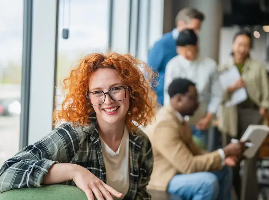 Smiling redhead woman student working in modern office startup
