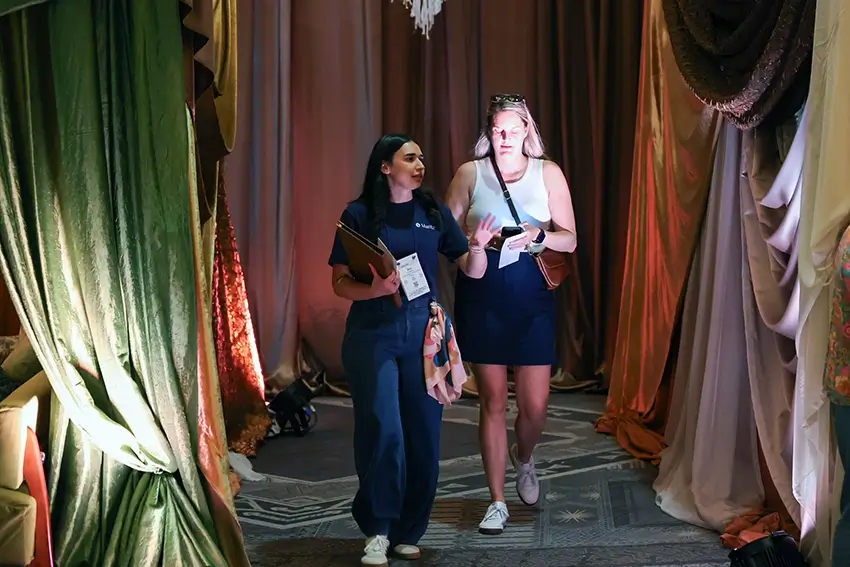 Woman at event walking another woman through a hallway
