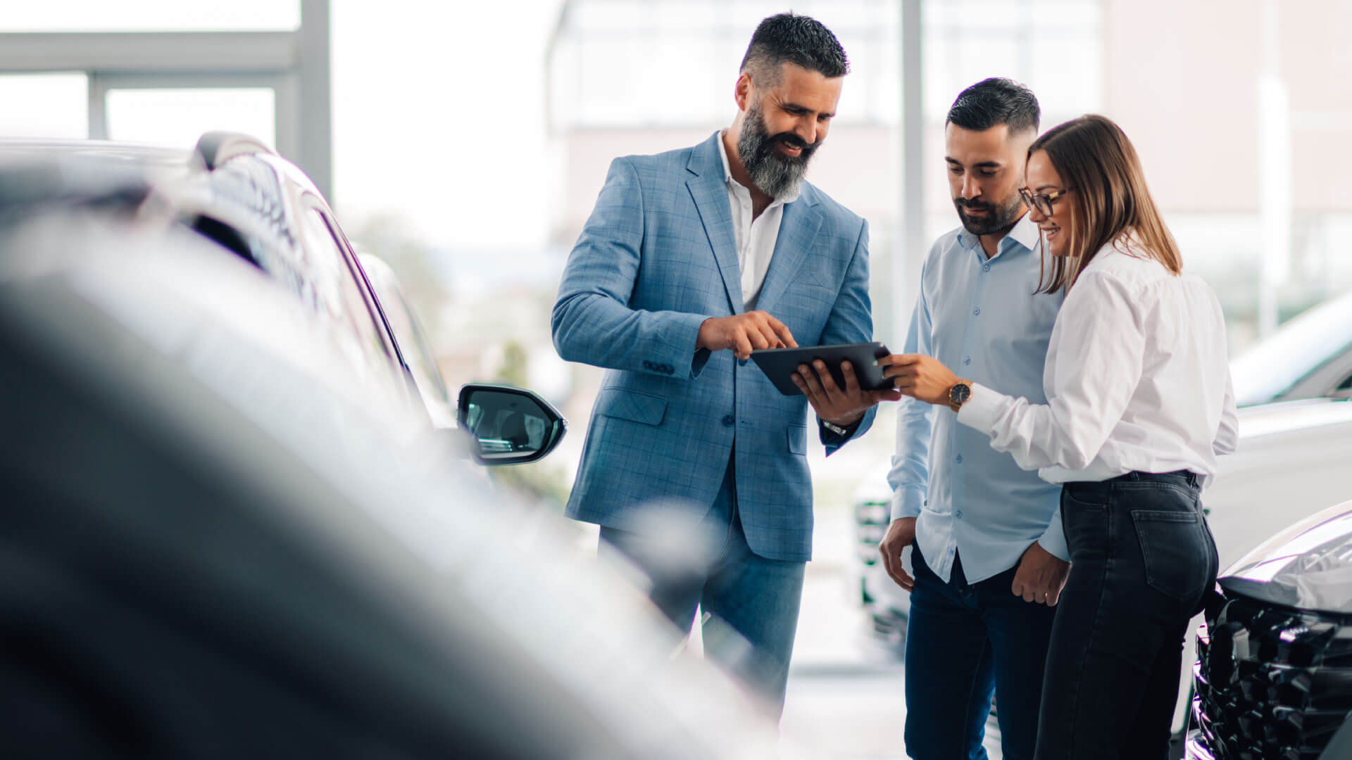 Automotive professionals reviewing dealership technology and digital performance data on a tablet